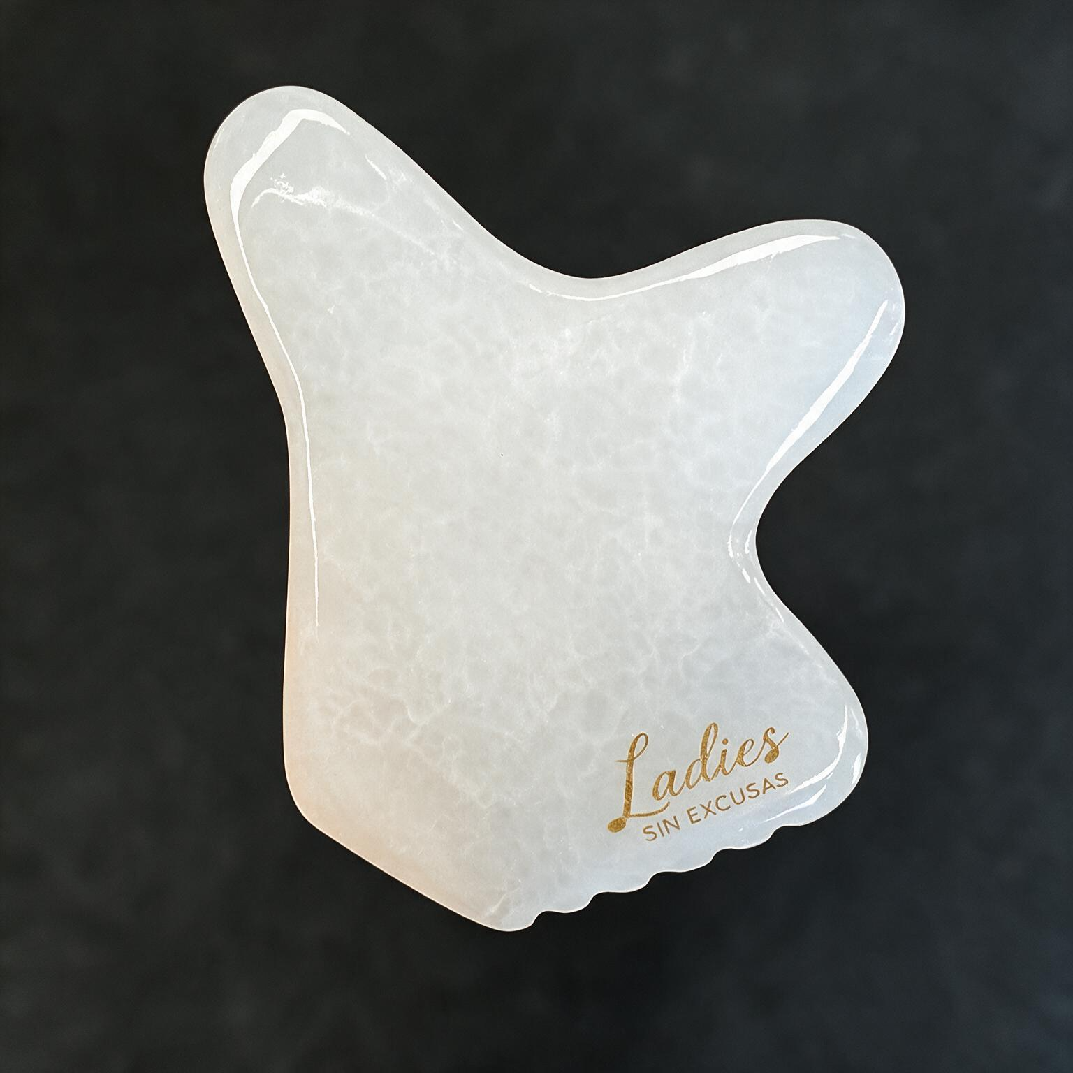 Gua Sha de ónix sobre fondo oscuro